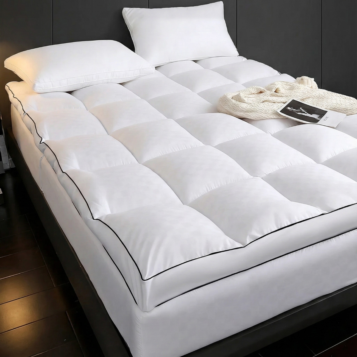 White mattress topper on a bed with pillows and a blanket in a bedroom setting.