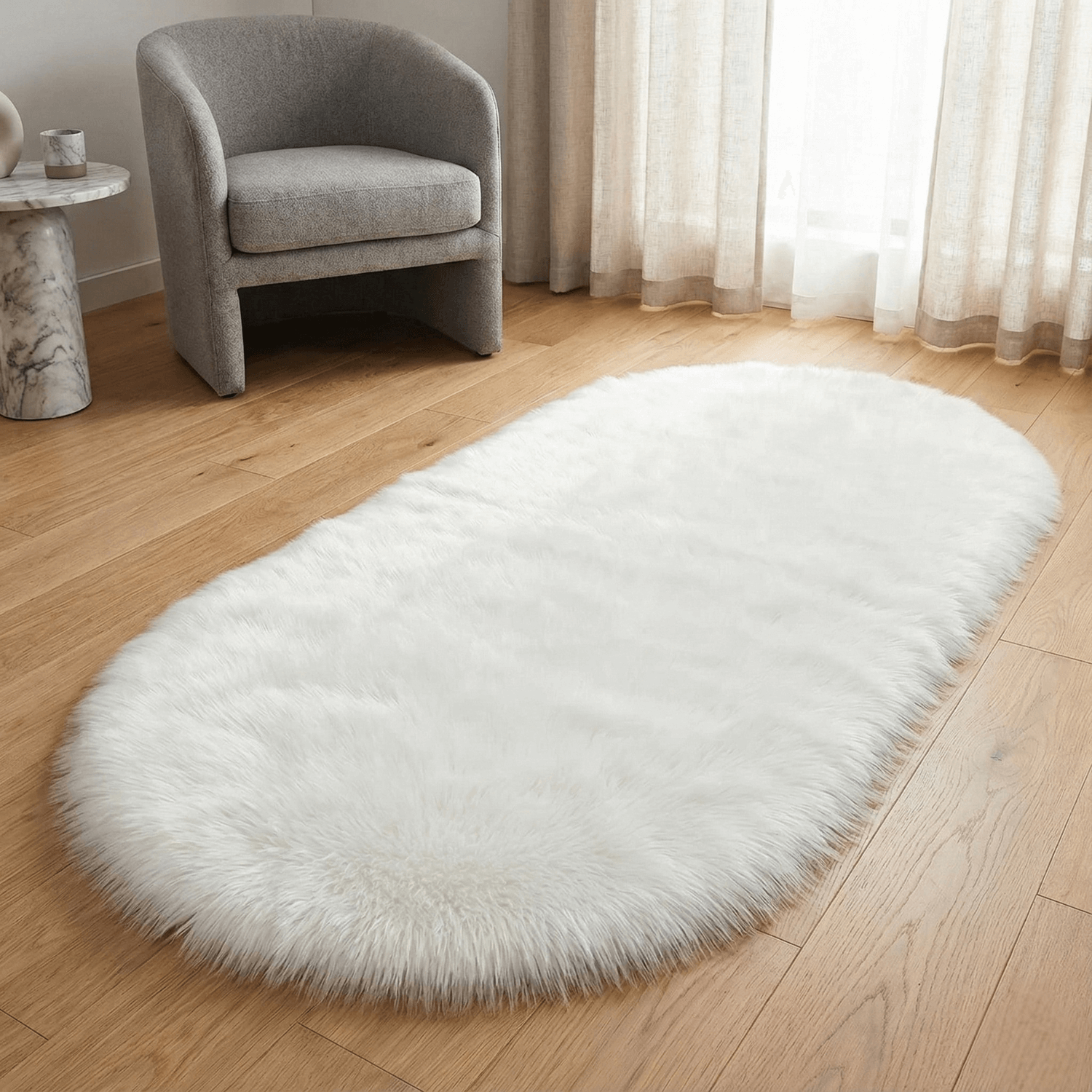 White fluffy rug on a wooden floor with a gray chair and curtains in the background.