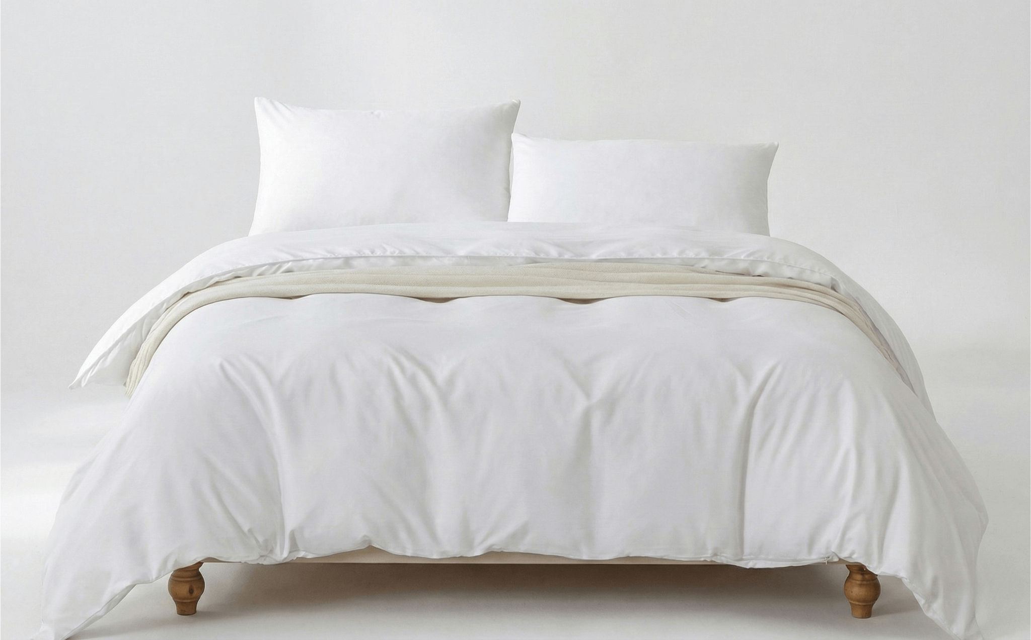 White bed with white bedding and pillows on a plain background
